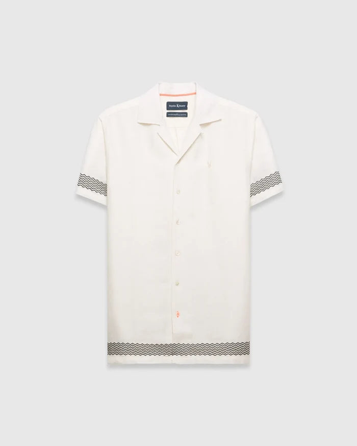 Mens Sunny Linen Shirt, an off-white relaxed linen camp collar shirt, features black zigzag patterns on sleeves and hem, an embroidered Psycho Bunny logo left chest, and orange collar trim.