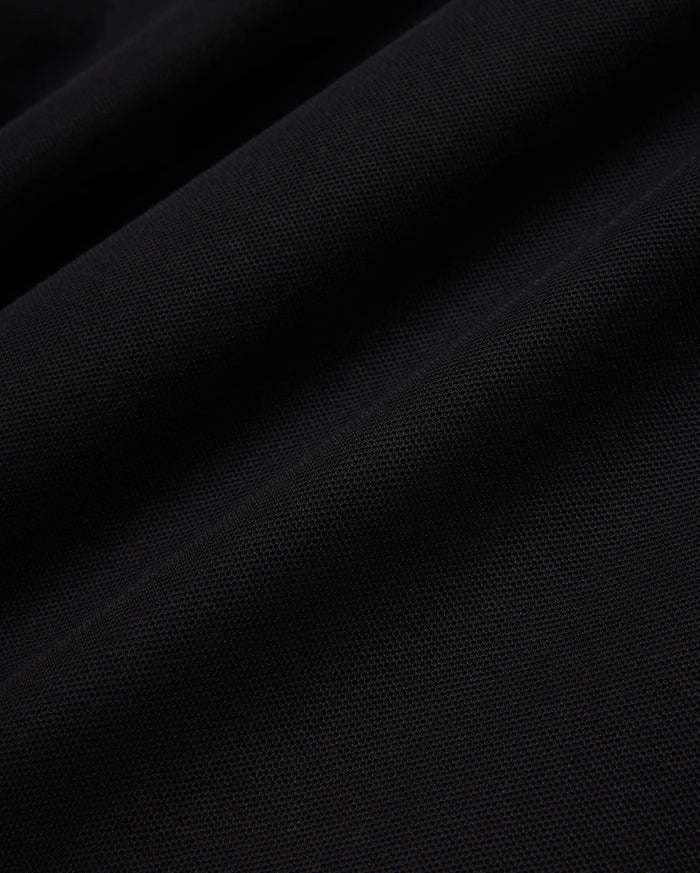 Psycho Bunny Mens Taylor Pique Tee in rich black, highlighting the premium, breathable pique knit fabric texture with subtle, elegant folds and shadows, perfect for refined streetwear.