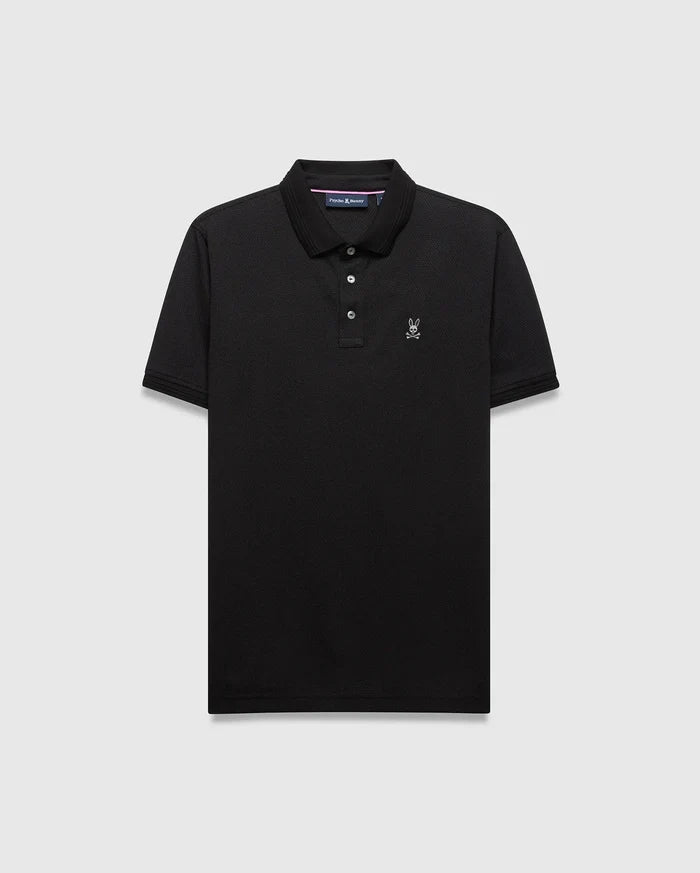 Mens Tiernan Pique Polo in black, classic fit, with a pique knit texture. Features a small white embroidered Psycho Bunny skull logo on the left chest, a three-button placket, and ribbed cuffs.
