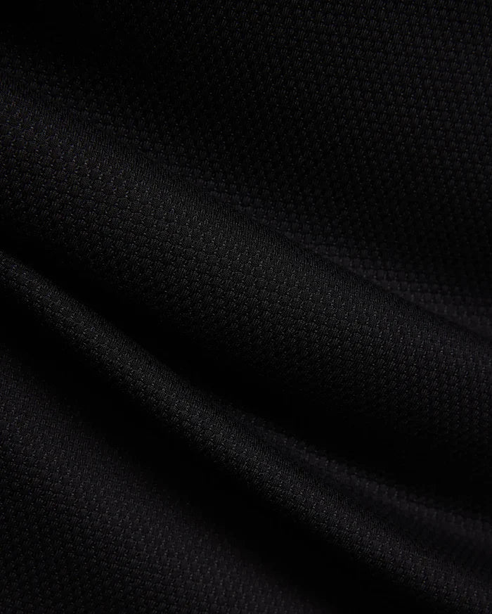 MENS TIERNAN PIQUE POLO in deep black, showcasing its premium, classic textured pique knit fabric with elegant folds, reflecting Psycho Bunny's refined streetwear aesthetic.
