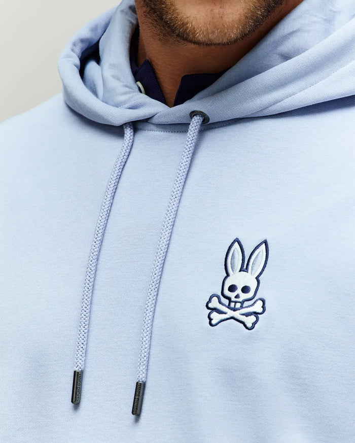 Mens Timothy 4k Bunny Hoodie, a light blue classic fit jersey hoodie with a small embroidered white and navy Psycho Bunny skull logo on the left chest and branded silver-tipped drawstrings.