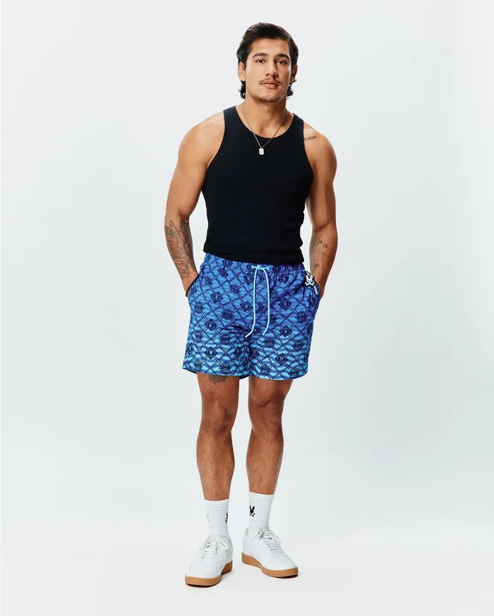 Mens Tobias Gradient Swim Trunk, a blue gradient all-over diamond pattern featuring repeating Psycho Bunny skull logos, with a white drawstring and small logo tag on the right pocket. Relaxed fit.
