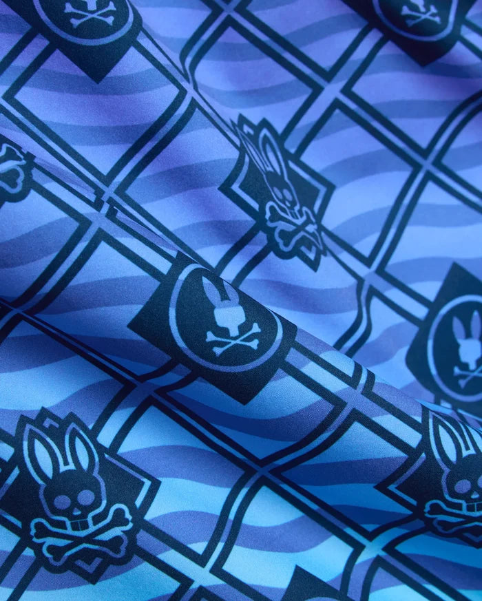Mens Tobias Gradient Swim Trunk in a blue and purple gradient, featuring an all-over geometric grid pattern with repeated Psycho Bunny skull logos on smooth woven fabric.