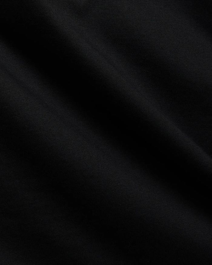 Close-up of the Mens Tobias Graphic Tee in deep black, highlighting its premium, soft cotton jersey knit fabric with subtle, flowing folds and a refined, smooth texture.