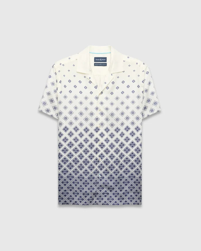 Mens Tobias Tencel Shirt, a relaxed fit cream short-sleeve camp collar shirt with a navy blue diamond pattern that intensifies downwards, featuring the iconic Psycho Bunny skull logo.