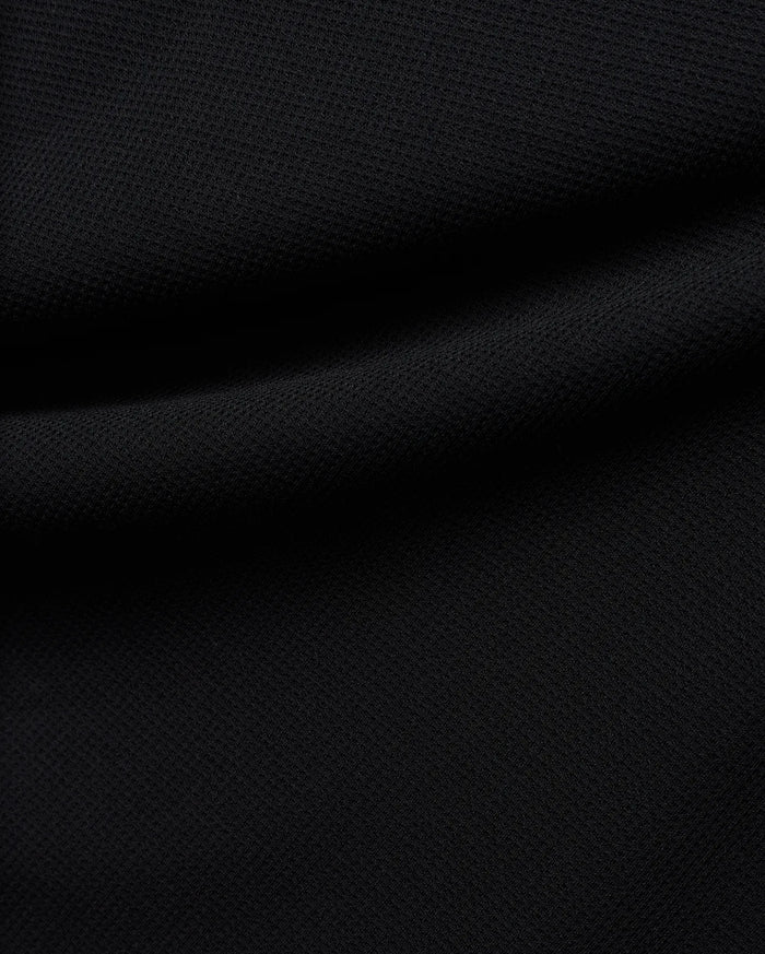 Premium black Tomas Waffle 1/4 Zip, showcasing its rich, deep black fabric with a prominent, textured waffle knit pattern and soft, flowing folds, embodying Psycho Bunny's refined streetwear.