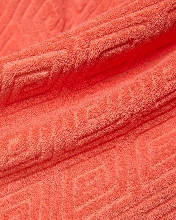 Mens Tristan Short in bold coral terry cloth, featuring a luxurious plush texture and an intricate, all-over embossed geometric maze pattern, reflecting refined streetwear style.