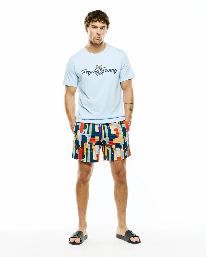 Light blue jersey t-shirt with large Psycho Bunny script logo on chest, paired with Mens Wes All Over Print Swim Trunk featuring a vibrant multi-color abstract pattern and subtle bunny skull logos.