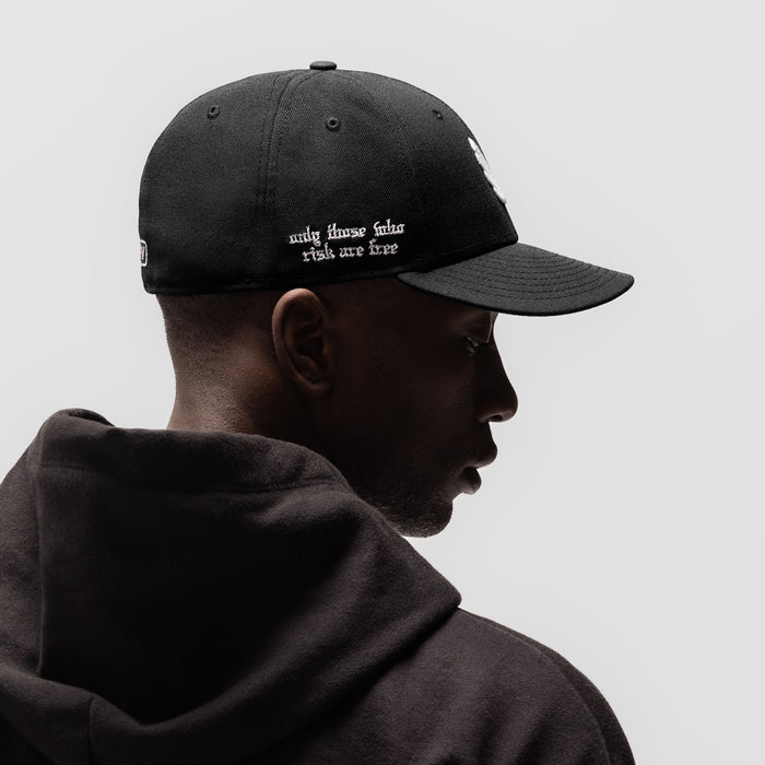 New Era 59Fifty Low Profile Hat in black with white embroidered text, worn by model in profile