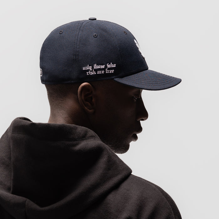 New Era 59Fifty Low Profile Hat in navy with white wings logo, worn by model in profile view