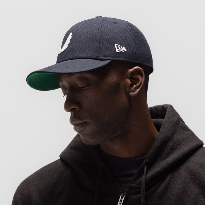 New Era 59Fifty Low Profile Hat in navy with white wings logo, worn by model in profile view