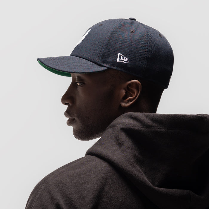 New Era 59Fifty Low Profile Hat in navy with white wings logo, worn by model in profile view