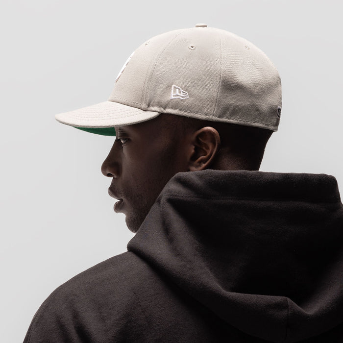 New Era 59Fifty Low Profile Hat in stone with white wings logo, worn by model in profile view