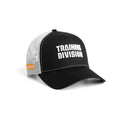 Flatlay of New Era 9Forty A-Frame Trucker Hat in black and white with 'Training Division' text, angled side view