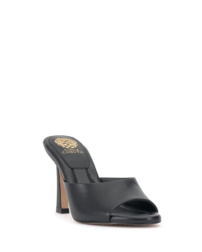 Introducing the Paigely Mule by Vince Camuto: a black minimalist mule with a flared heel, featuring an open toe and a thick strap across the foot. The insole is detailed with a gold embossed design near the heel.