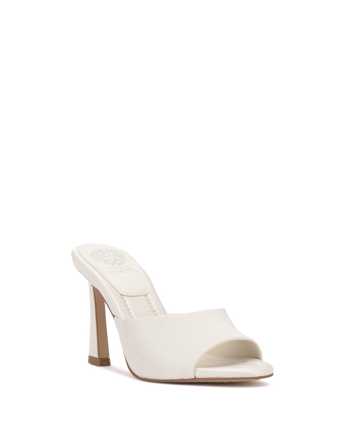 The Paigely Mule by Vince Camuto is a white open-toe satin mule featuring a single wide strap across the front, a flared heel, and a cushioned pillow footbed, shown against a plain white background.