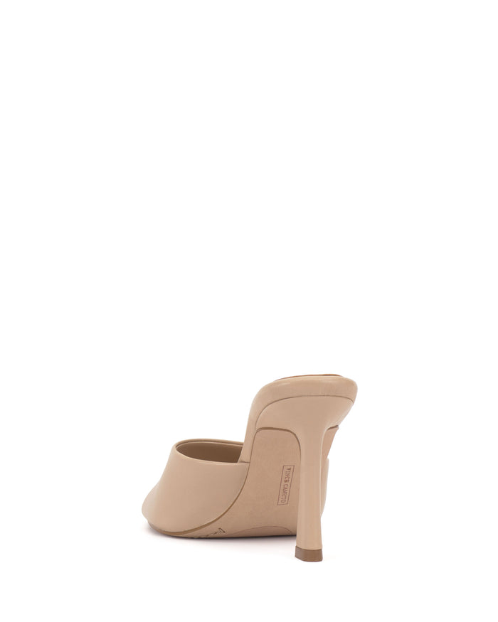 The Vince Camuto Paigely Mule is a beige minimalist high-heeled shoe, shown from the back with a closed toe and a slender stiletto heel.