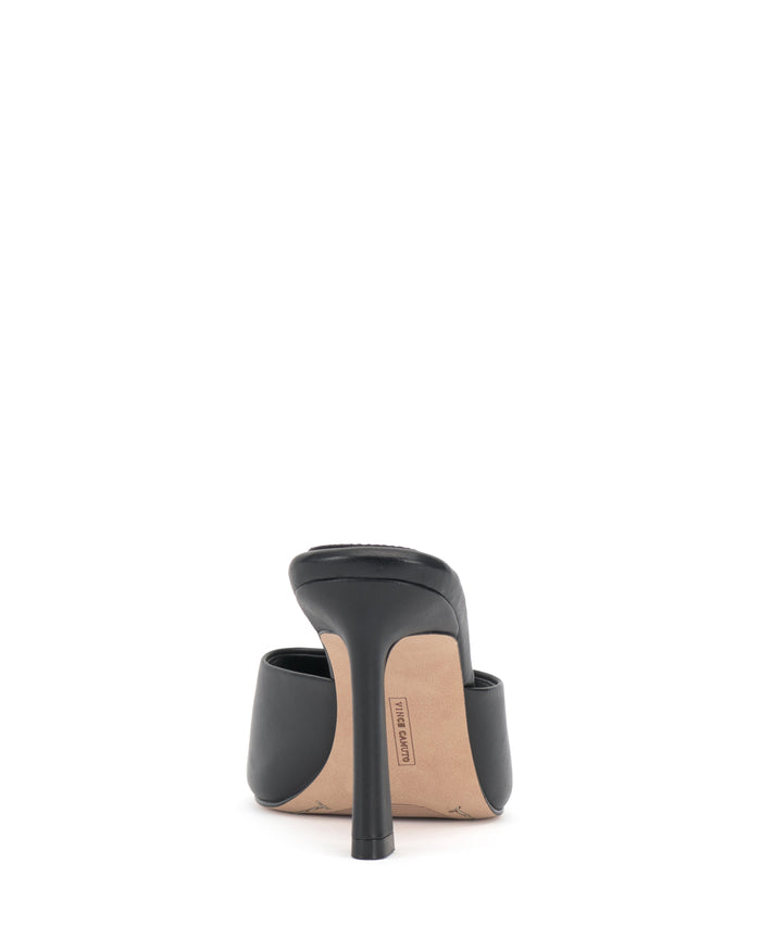 The Paigely Mule by Vince Camuto is a black minimalist high-heeled shoe, shown from the back with a flared heel and sole, set against a plain white background.