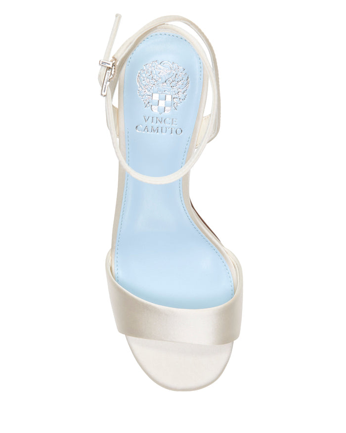 Top view of the Vince Camuto Pendreya Platform Sandal in white, featuring a light blue insole, ankle strap, and the Vince Camuto logo printed in silver on the footbed. This stylish platform sandal boasts a block heel that combines stability with a touch of retro flair for your look.