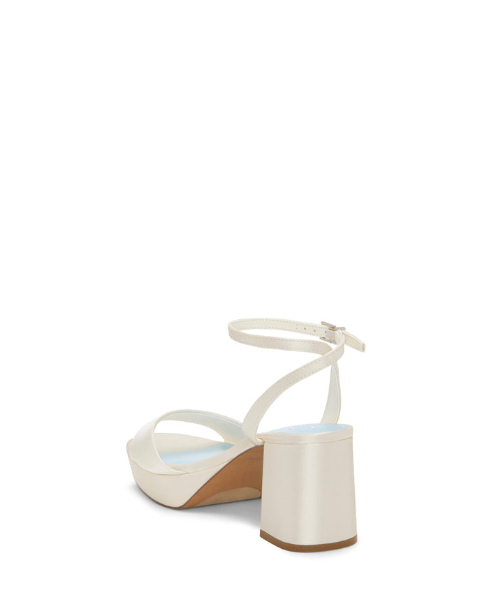 The Vince Camuto Pendreya Platform Sandal is displayed from a rear angle against a white background, showcasing its white color, block heel, ankle strap, and open toe design that evokes a subtle retro elegance.