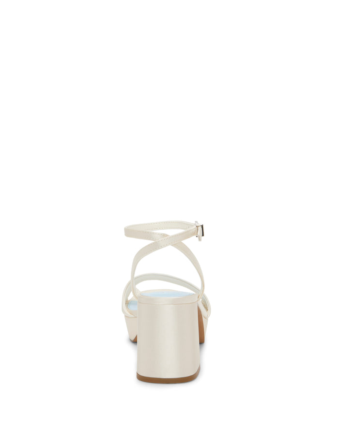 The Vince Camuto Pendreya Platform Sandal is shown from the rear, featuring a white retro crisscross design, block heel, ankle strap, open back, and a light blue insole.