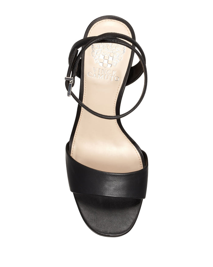 The Pendry Platform Sandal by Vince Camuto is a black open-toe sandal with a wide front strap and a thin ankle strap featuring a buckle, shown from above. Inspired by ’70s fashion, this retro design includes a beige insole with the Vince Camuto logo visible near the heel.