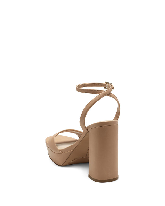The Pendry Platform Sandal by Vince Camuto features a beige high heel with an ankle strap and thick block heel, inspired by 70s sandals, shown from the back left side against a white background.