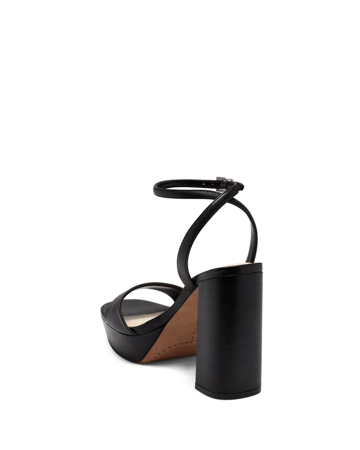 The Pendry Platform Sandal by Vince Camuto features black leather, an ankle strap, a cylindrical block heel, and an open toe in a classic ’70s silhouette—presented here from the back on a white background for a modern update to retro style.