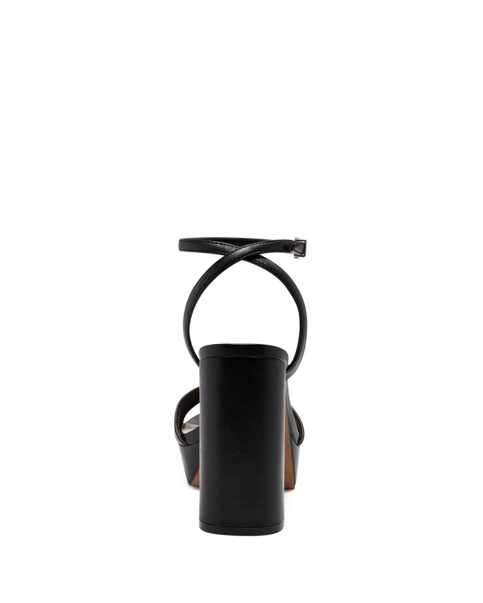 The Pendry Platform Sandal by Vince Camuto is a black, ’70s-inspired high-heeled sandal featuring a block heel and ankle strap, shown from the back against a white background.
