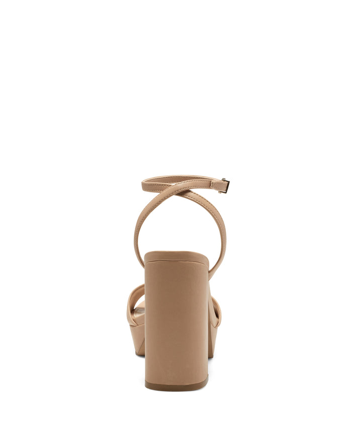 The Vince Camuto Pendry Platform Sandal is a tan high-heeled platform sandal viewed from the back, showcasing a thick block heel, a platform sole, and a thin ankle strap with buckle—capturing the timeless style of classic 70s sandals.