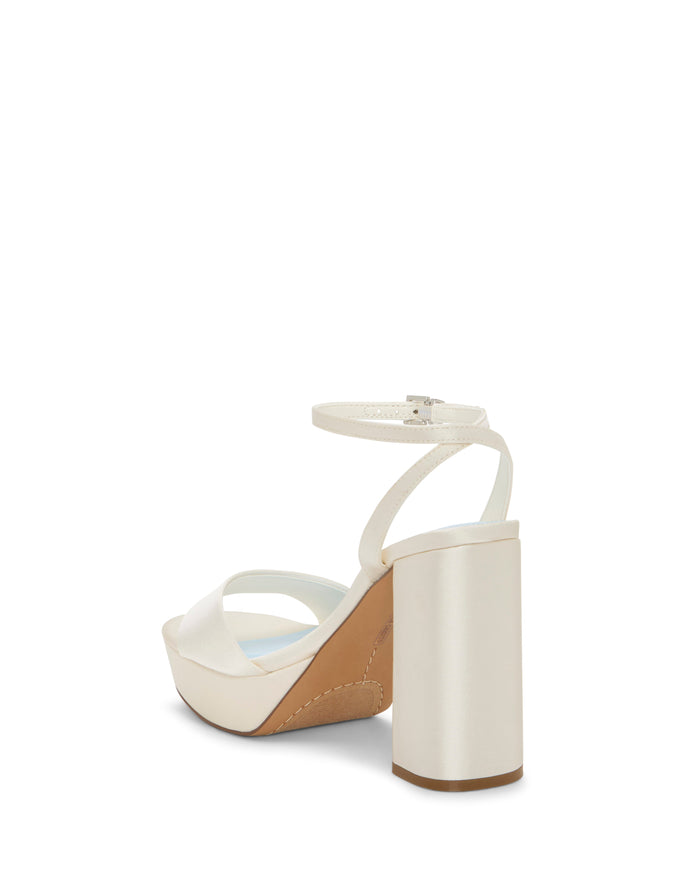 The Pendry Platform Sandal by Vince Camuto features a white finish, high block heel, ankle strap, and cross-toe band that together exude a subtle retro vibe; it is displayed at an angle from the back against a plain white background.