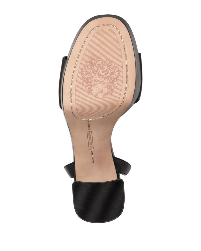 The underside of the Pendry Platform Sandal by Vince Camuto reveals a tan sole with a textured heel, detailed stitching, and an ornate logo design near the toe area—features that highlight its unmistakable ’70s style charm.