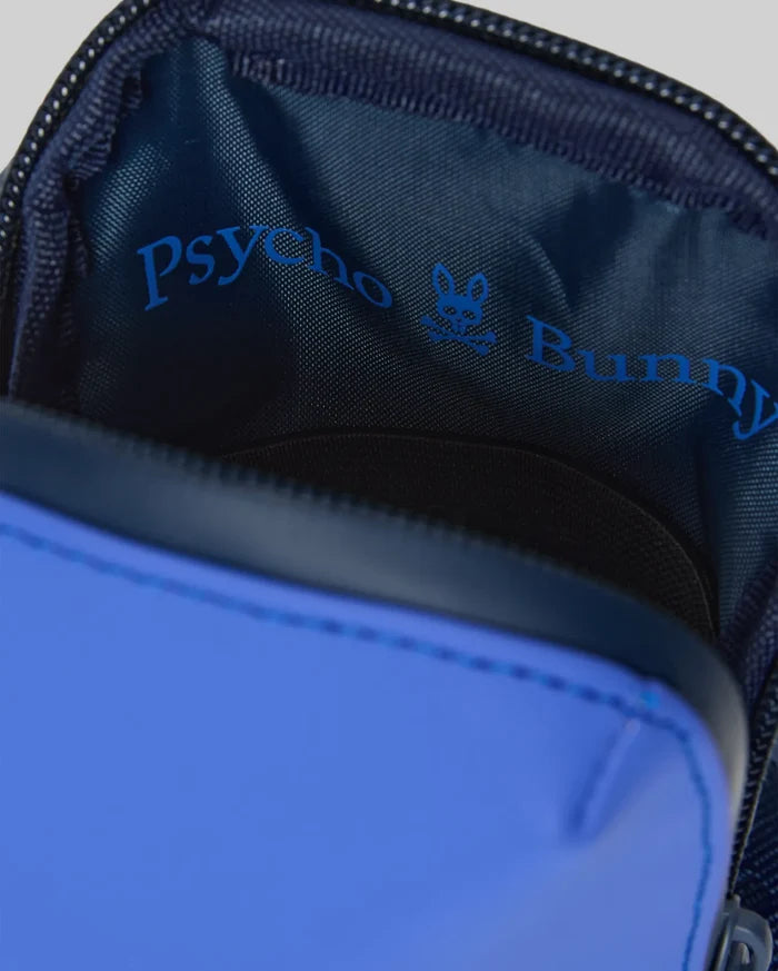 Rubberized Crossbody Bag in royal blue with a smooth exterior, revealing a dark navy woven interior lining featuring a prominent bright blue Psycho Bunny text logo and skull graphic.