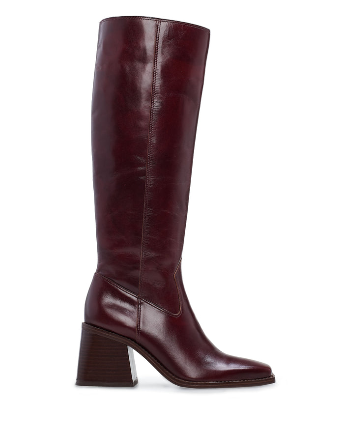 The Sangeti Narrow Calf Boot by Vince Camuto is a tall, dark brown leather knee-high boot with a flared block heel and pointed toe, shown in side profile on a white background. This best-selling style features a sleek silhouette that effortlessly elevates any look.