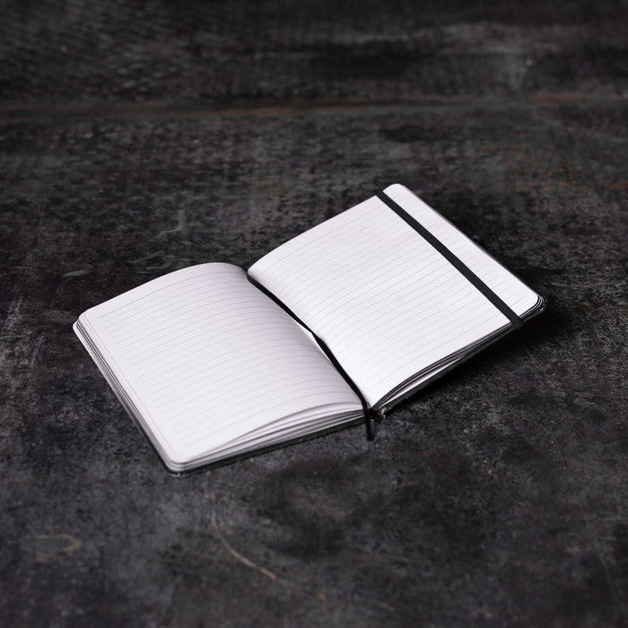Flatlay of SM'22 OTWR Notebook in white and black, open pages view on dark textured surface