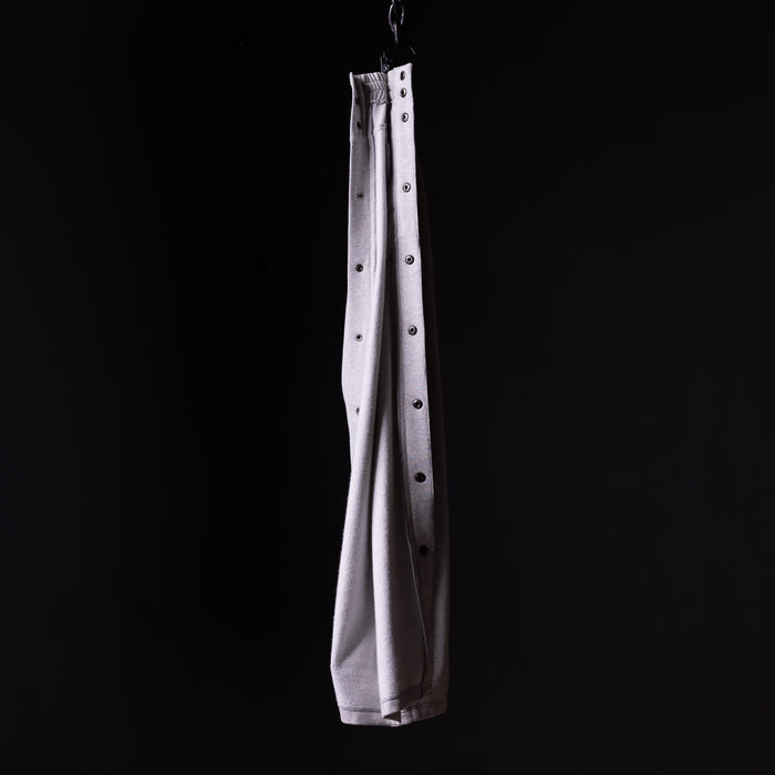 SP'22 Tearaway Jogger in light gray, hanging from hook against black background