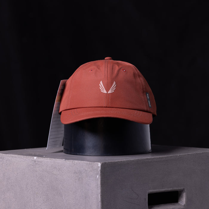 flatlay SP'23 Hybrid Sport Cap in rust red with white wing logo, front view