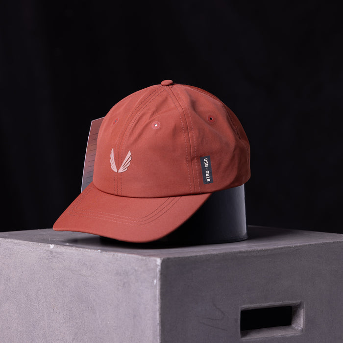 flatlay SP'23 Hybrid Sport Cap in rust red with white feather logo, front view