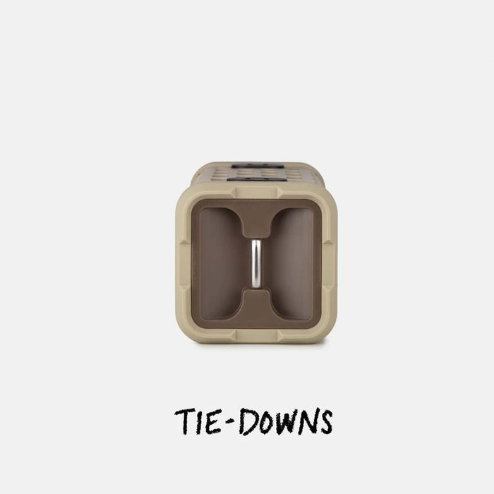End view of the tan Turtlebox Ranger speaker showing tie-down slots and an integrated metal bar for securing the speaker during transport.