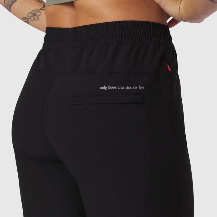 Black ripstop relaxed track pant worn by model, back view showing pocket detail and text