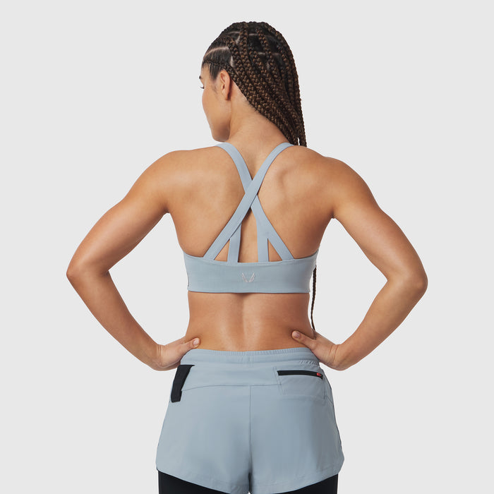 Light sky LYCRA® hybrid sports bra with cross-back straps, worn by model from behind