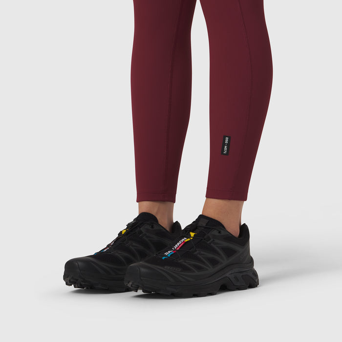 Crimson ribbed leggings worn with black athletic shoes, lower body view