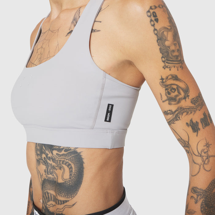 W096 LYCRA® ADAPTIV Racerback Sports Bra in Slate Grey, worn by model with tattoos, side view
