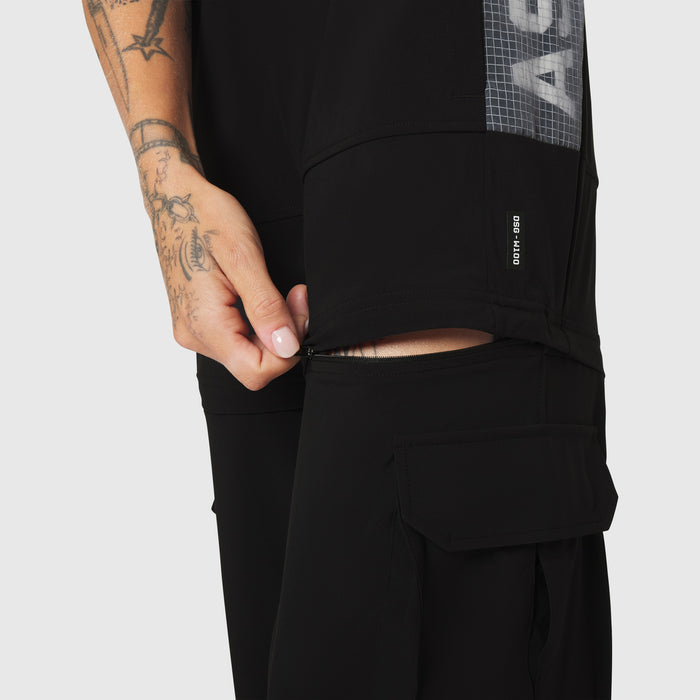 W100 2-in-1 Convertible Pant in black, worn by model showing zippered cargo pocket detail