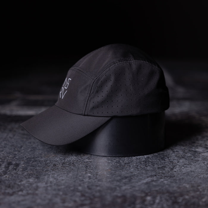 flatlay WN'22 Vented Hat in black, side angle view on textured surface