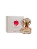 A bottle of Vince Camuto Women 1.0 oz Eau de Parfum Spray, adorned with a decorative gold cap, sits beside its stylish white and gold box featuring a distinctive red wax seal design. This elegant fragrance unveils notes of Bulgarian rose and patchouli, lending depth and sophistication to the scent experience.