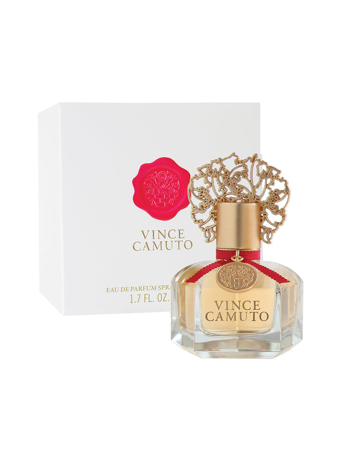 A bottle of Vince Camuto Women 1.7 oz Eau de Parfum Spray, adorned with an ornate gold cap, sits in front of a white box accented with a pink crest and gold lettering. Both the bottle’s label and the box display “Vince Camuto” and “Eau de Parfum Spray,” suggesting an alluring floral fragrance delicately layered with sensual vanilla patchouli notes within.