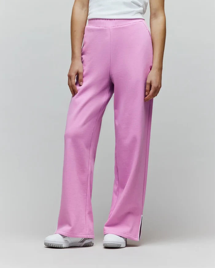 Womens Daisie Fleece Joggers in bright pink, with a relaxed wide-leg fit, soft fleece texture, small embroidered bunny skull logo on the left thigh, and white piped side leg slits.