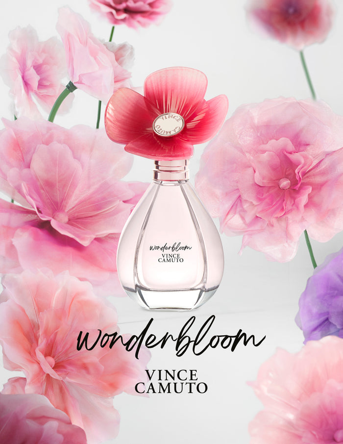 The Wonderbloom 3-Piece Set by Vince Camuto features a pink perfume bottle adorned with a large pink flower cap, surrounded by soft, colorful flowers, capturing delicate notes of white freesia and subtle hints of sandalwood.